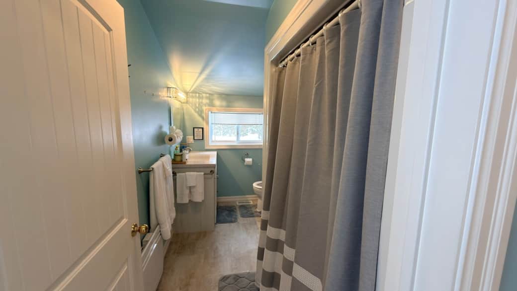 Bright and spotless full bathroom with a shower–tub combo, fresh towels, and complimentary toiletrie