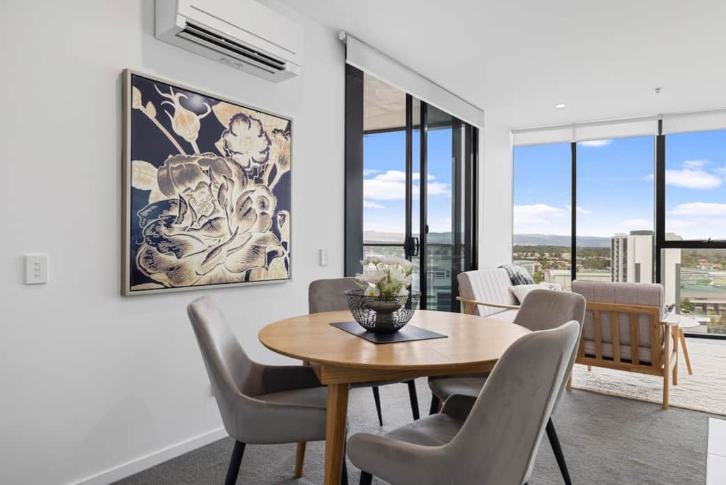 The dining area offers a delightful experience with its round table set for four, overlooking the city through the large windows. The natural light and scenic view make every meal special, enhancing your dining experience and having a relaxation.
