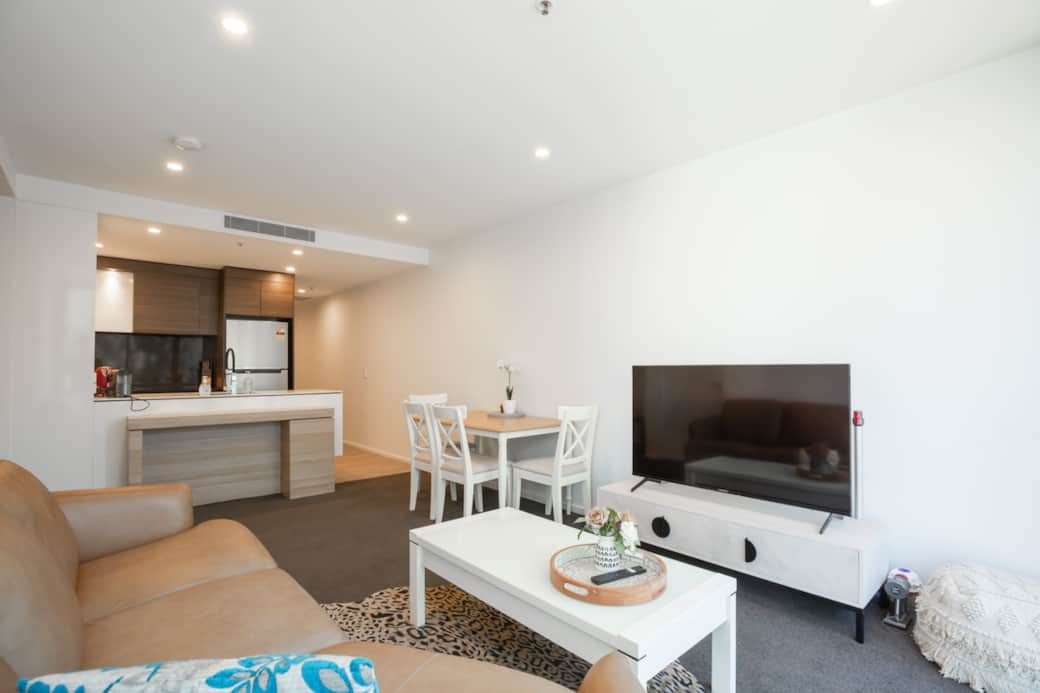 Welcome to our spacious open-plan living area, where comfort meets style. The large sofa and flat-screen TV create a cozy entertainment space, while the dining area invites you to enjoy meals in elegance.