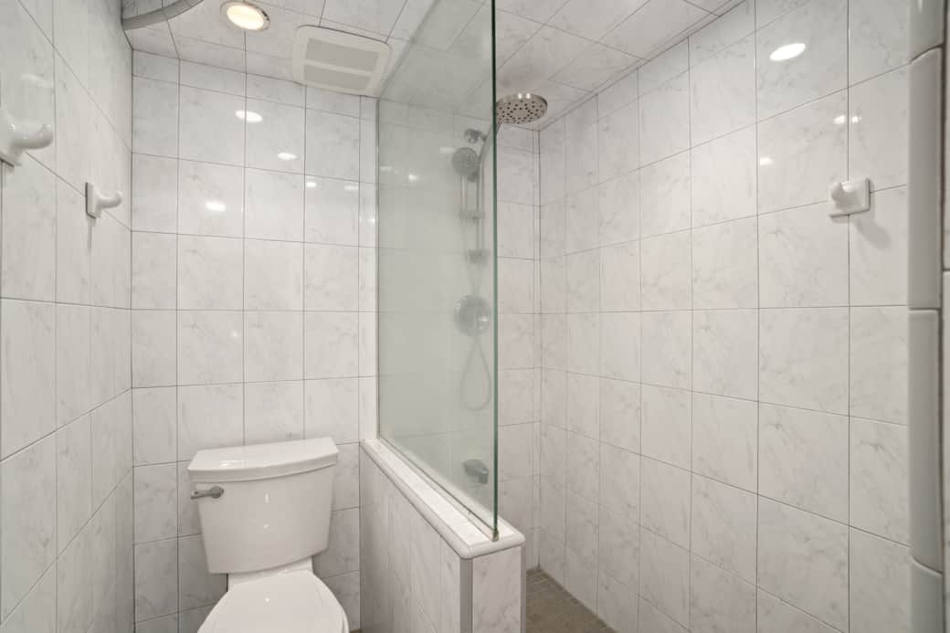 Clean, modern shower with full tile surround and glass panel.