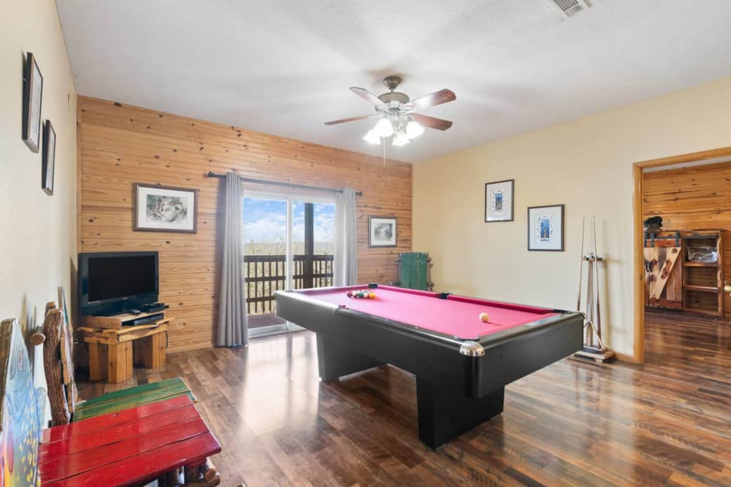 Enjoy friendly competition in the game room featuring a vibrant pool table, rustic charm, and sliding doors that open to scenic views of the White River and Inspiration Valley.
