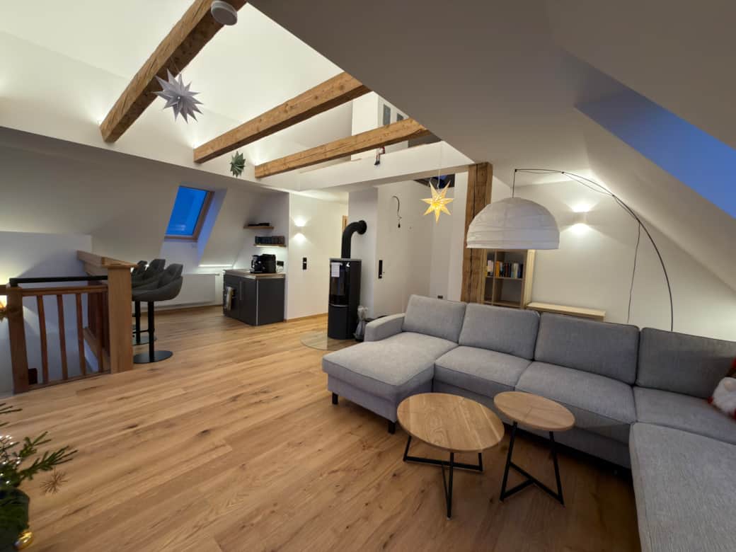 Gemütliches Wohnzimmer im Dachgeschoss mit Kaminofen, Teeküche und Panoramafenster mit Bergblick .