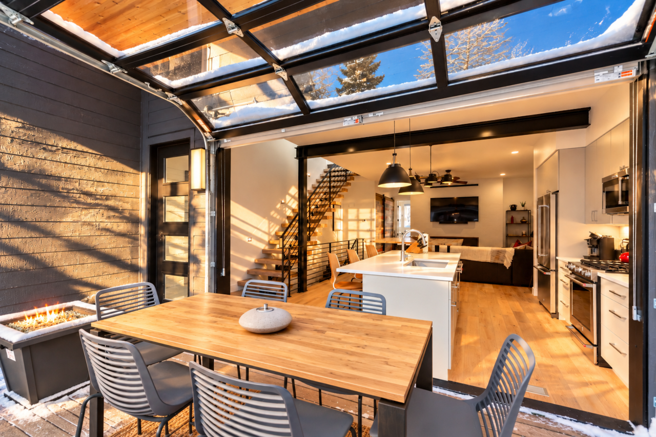 Garage door opens to the outdoor kitchen table and grill area