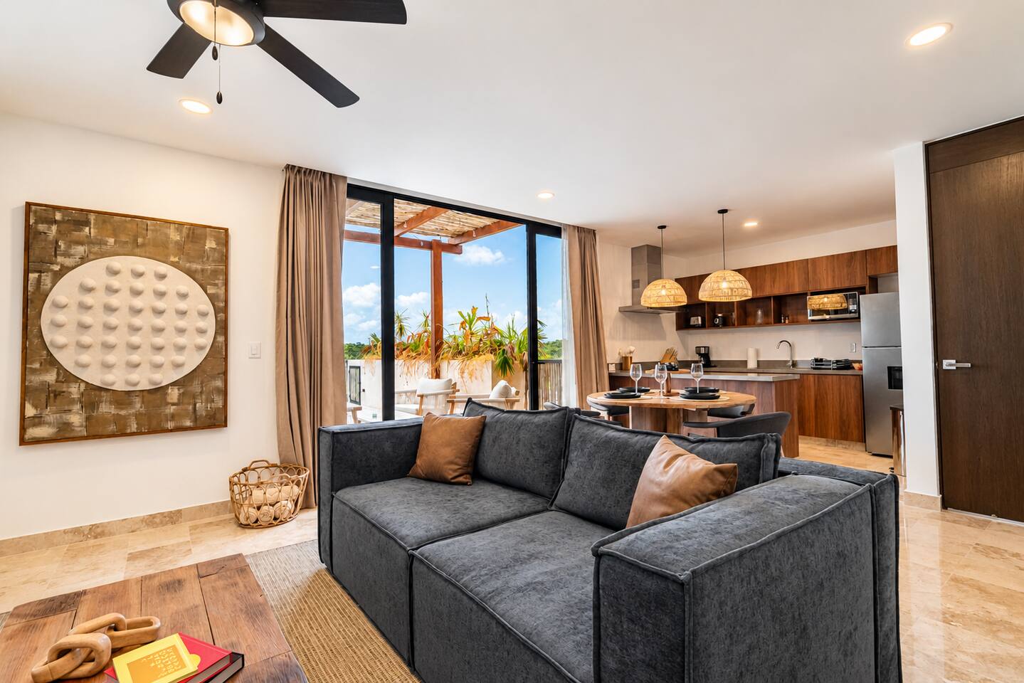 Relájate en la luminosa sala con aire acondicionado, cómodo sofá seccional y ventilador de techo, además de acceso directo a tu terraza privada y alberca con vista a la exuberante selva de Tulum.