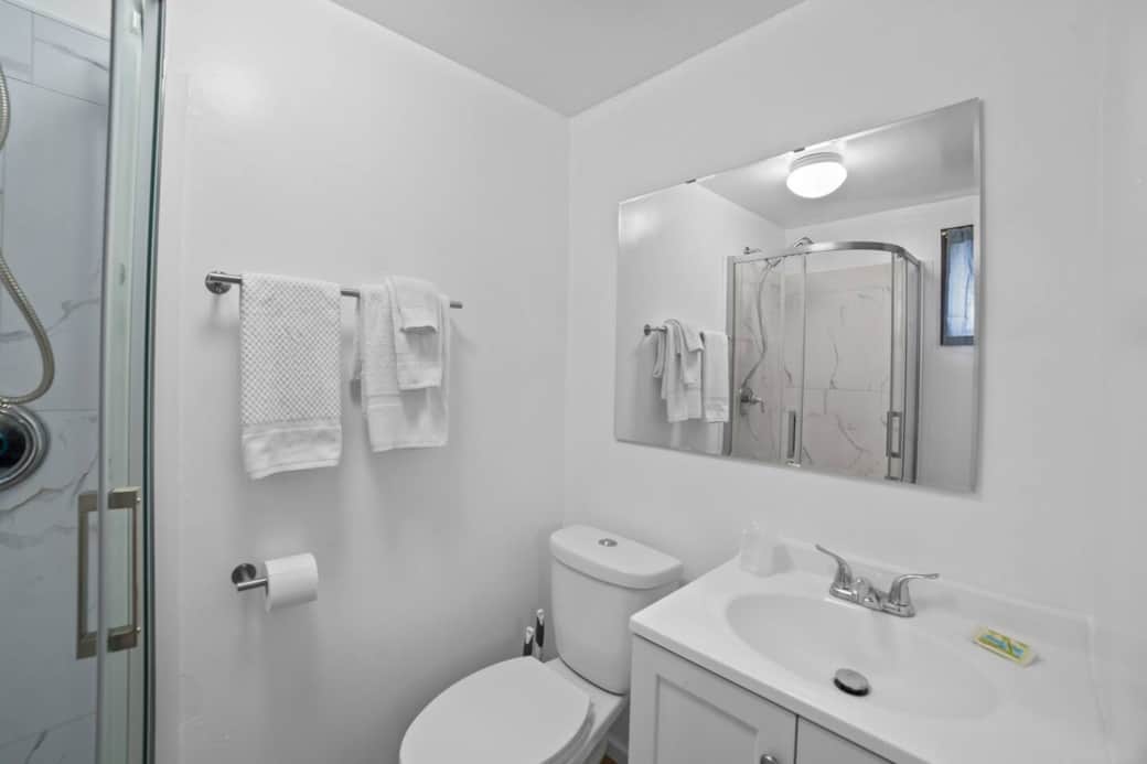 Pristine bathroom with fresh white towels, sleek vanity, and a glass-enclosed shower for a refreshing start to your day.