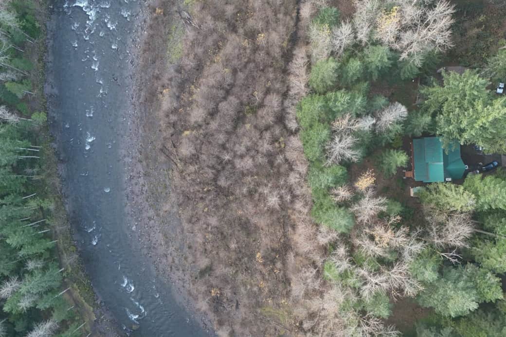 Drone shot showing the cabin on the right and the sandy river on the left. 