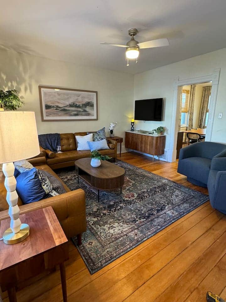 Inviting living room with a leather sofa, warm hardwood floors, and a stylish mid-century vibe.