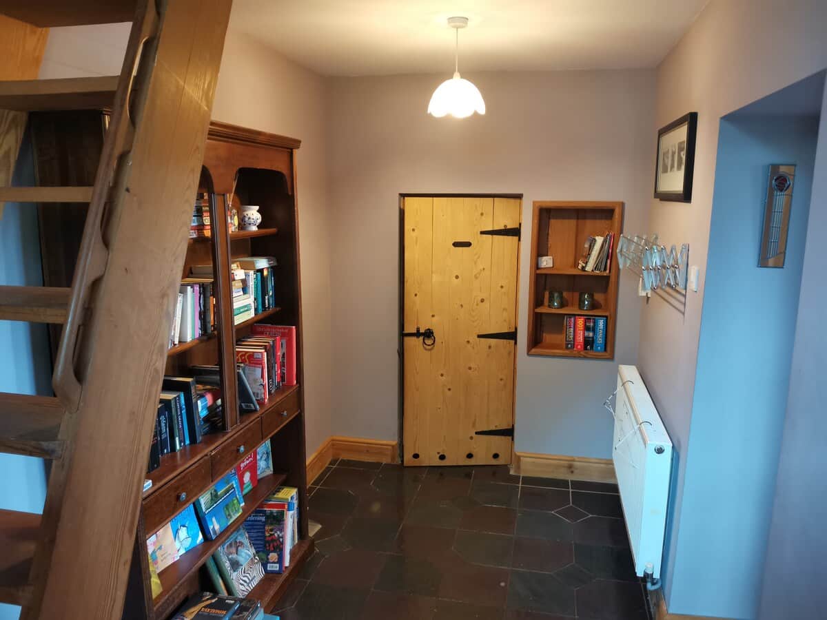 The hallway has a large bookshelf and the entrance to the bathroom, as well as the steps up to the loft bedroom and doorway into the main living area. 