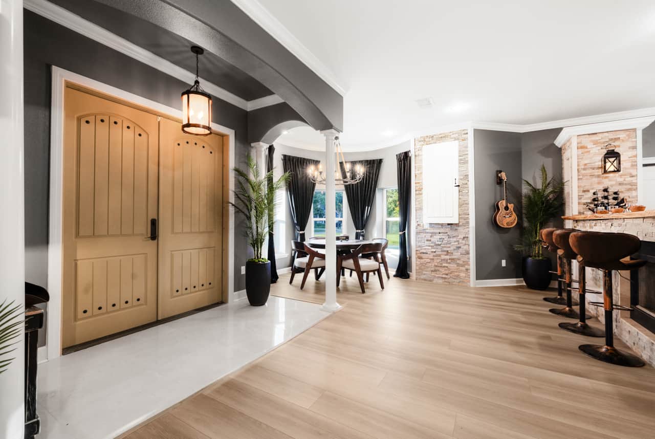 Open-concept entry with poker nook, dartboard wall, and bar with cozy fireplace seating.