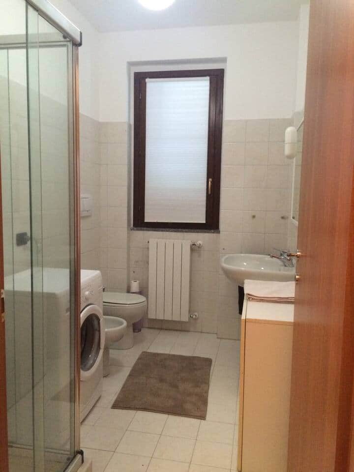 Bathroom with washing machine, shower and sink 