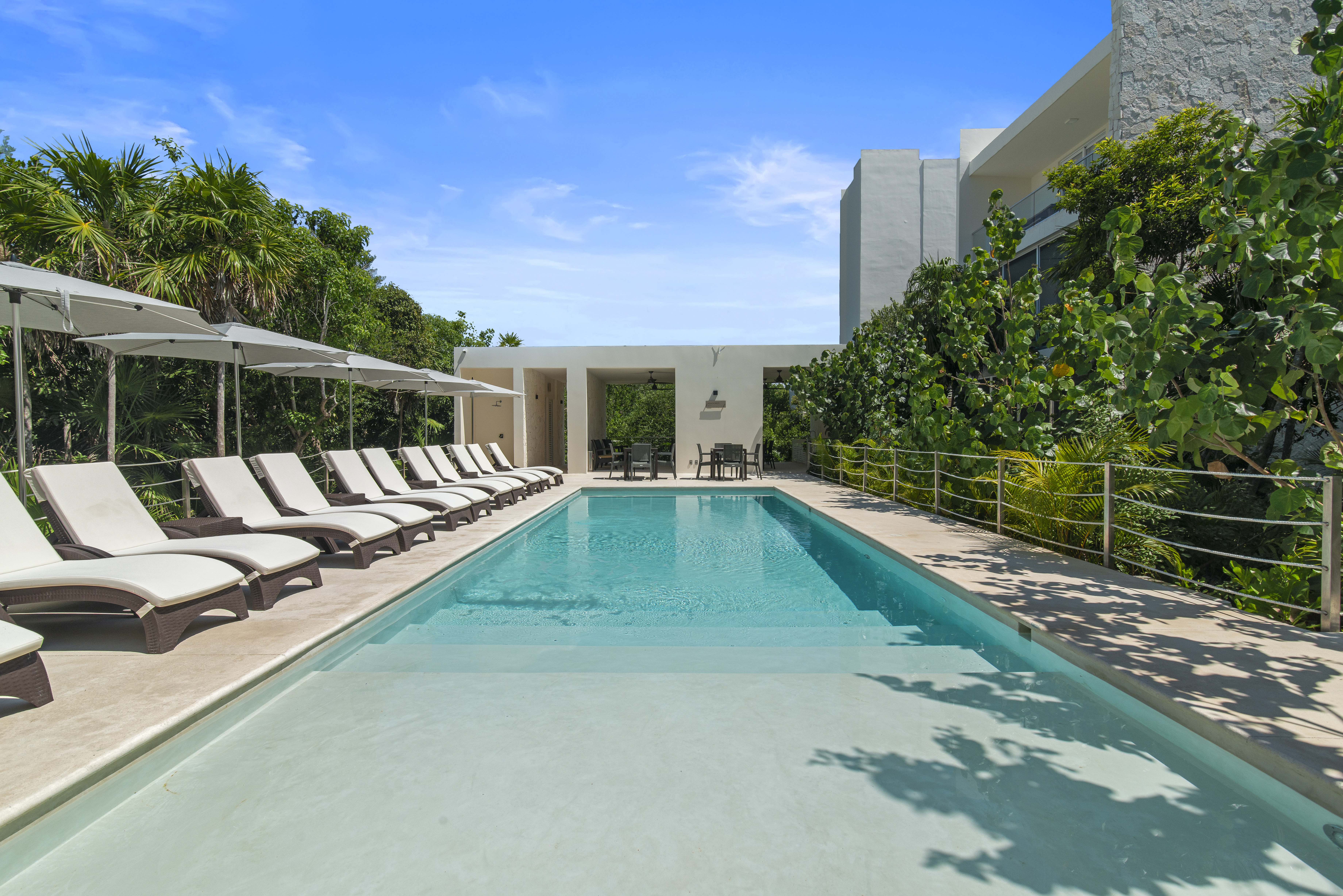 Relax by the pool with sun loungers, shaded umbrellas, and a peaceful tropical atmosphere.