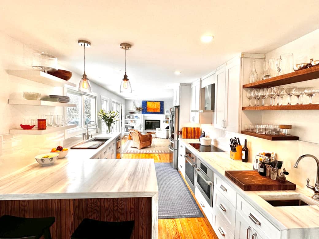 Open-concept kitchen clad in imported white marble and stainless steel appliance by Bosch & LG