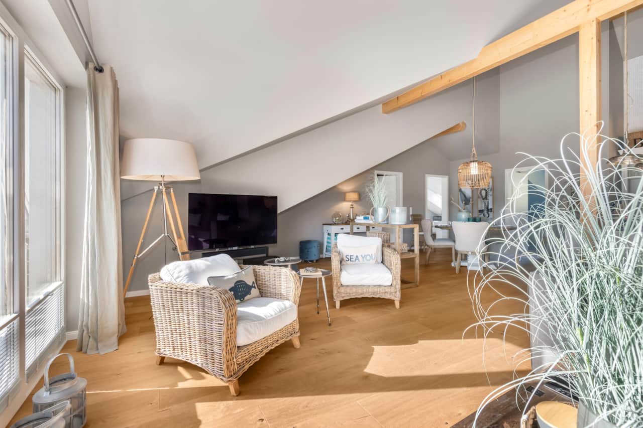 Modernes Wohnzimmer mit Dachschräge und Holzbalken, gemütlicher Sofaecke und heller Einrichtun