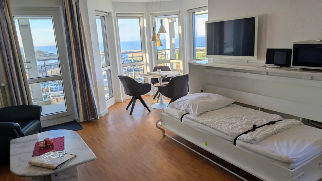 Compact living space with fold-down bed and sea view - living room