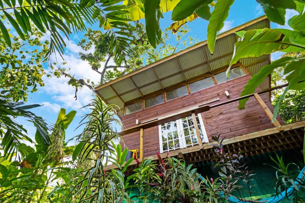 Exterior view of the elevated surf cabin surrounded by jungle. Features a private balcony with a covered roof and large windows that let in natural light, blending modern design with the tropical landscape in Big Creek, Bocas del Toro, Panama.