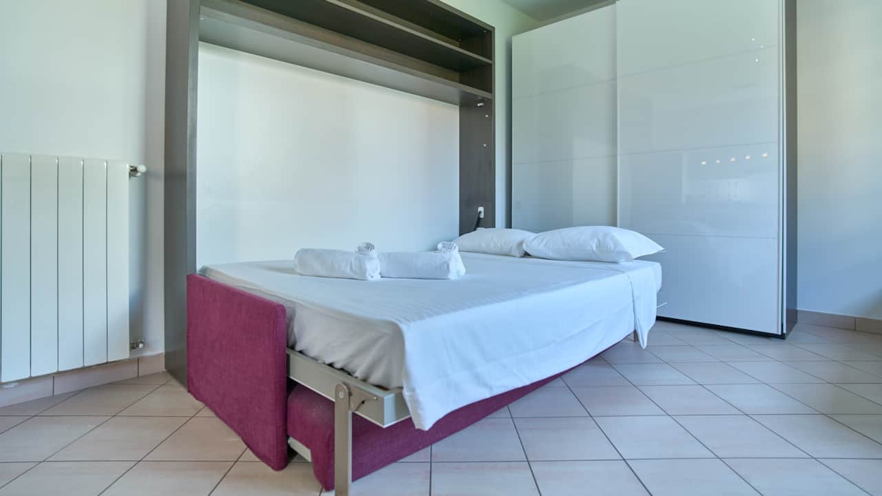 Dormitorio con cama, armario y ventana a las casas, en Monza