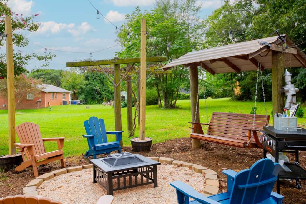 As the sun sets, gather around the fire pit under twinkling string lights, sinking into Adirondack chairs or swaying  on the covered porch swing. With laughter in the air and open sky above, this backyard invites slow evenings and lasting memories.
