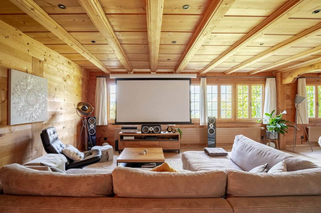 Unwind in the spacious living room, where breathtaking mountain views, a cozy tiled stove, and a state-of-the-art home theater await.