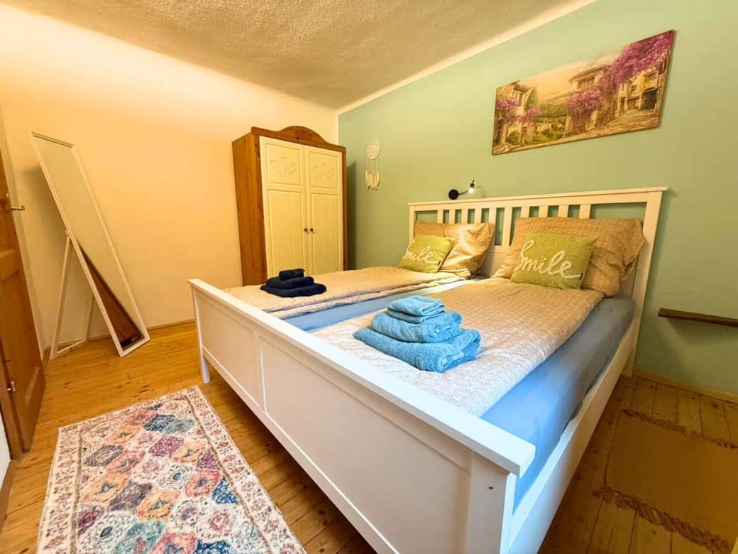 Schlafzimmer mit Doppelbett, Kleiderschrank und Spiegel. Fenster mit AUsblick auf den Fluss