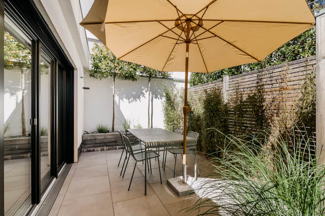 Private Terrasse mit Tisch und gemütlichen Sitzgelegenheiten im Grünen.
