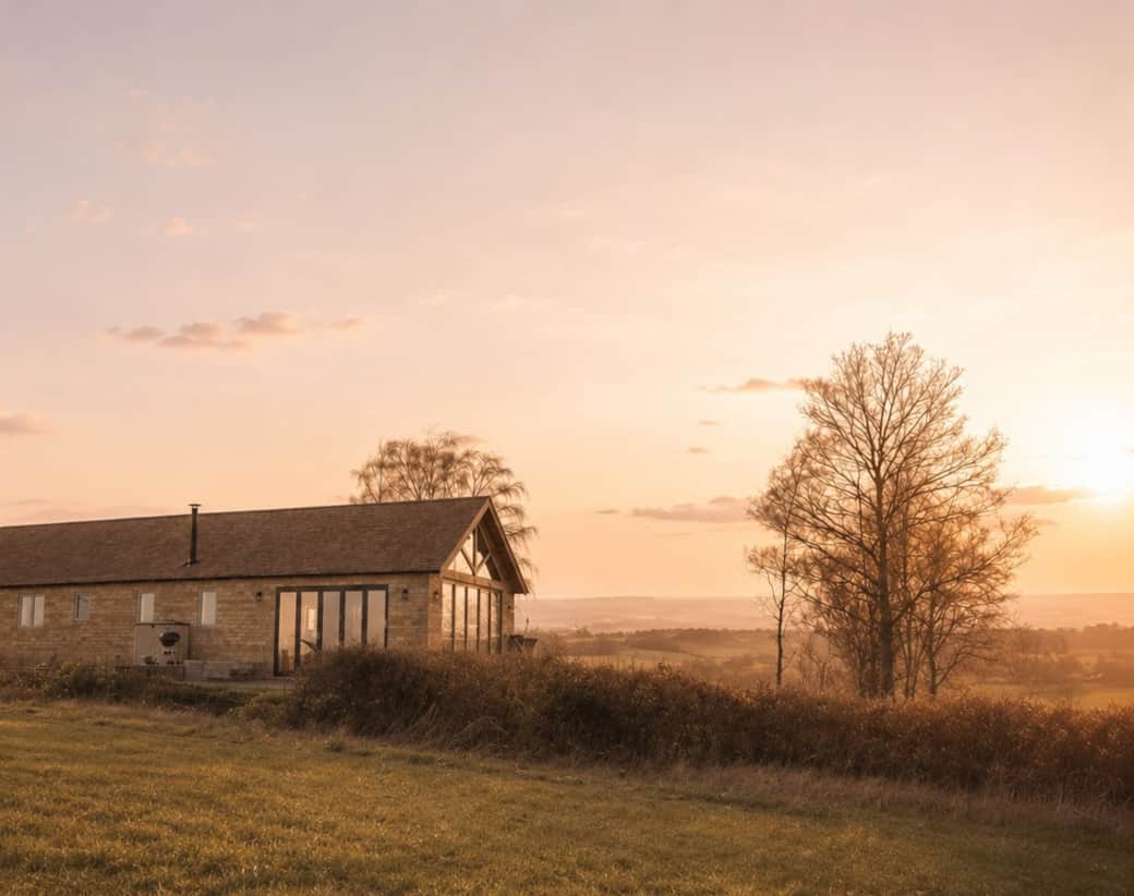The Barn on its hilltop with countryside beyond in soft evening light