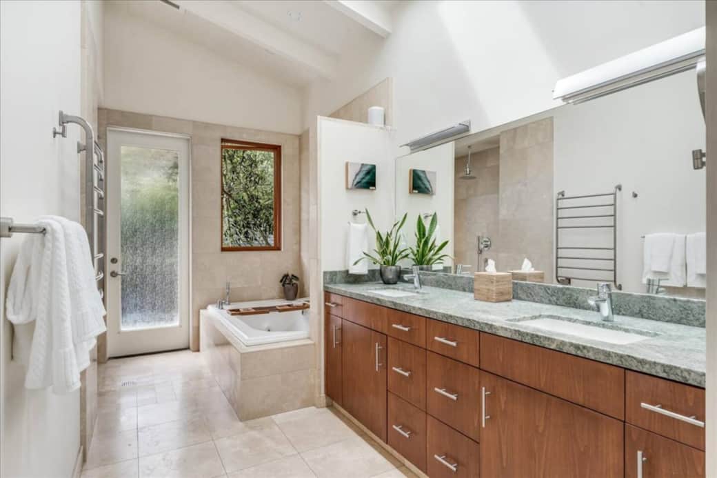 Primary bathroom with double sinks, features a soaking tub, and direct outdoor access -- perfect for returning to the retreat post surf!
