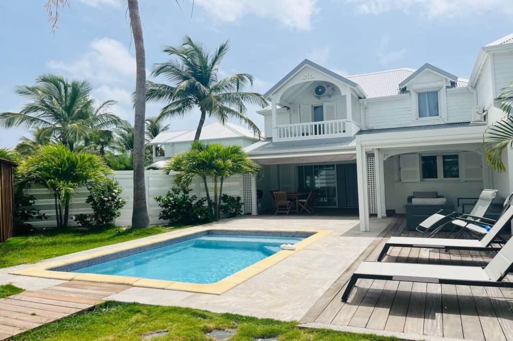 Pool with deck chairs and front of Villa Soliti
