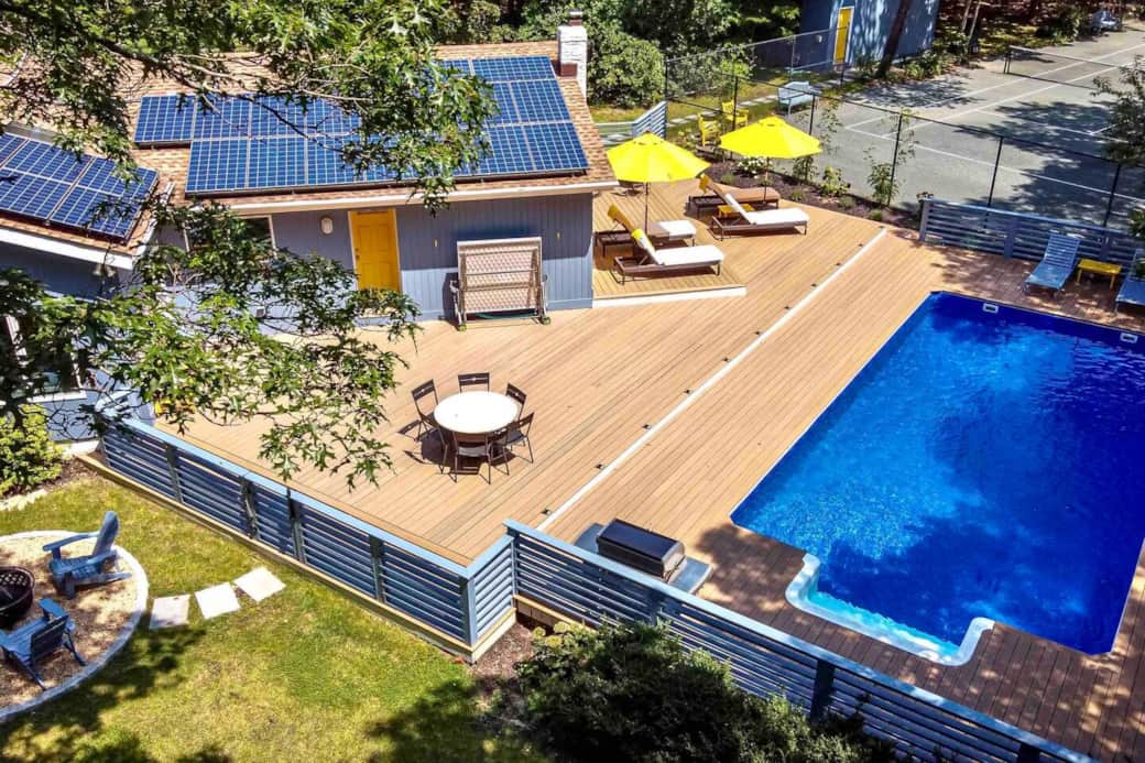 Solar powered and efficient.  View of the outdoor fire pit; pool deck (with outdoor dinning table, ping pong table, Weber BBQ grill, and multiple sun loungers); heated pool and tennis court.
