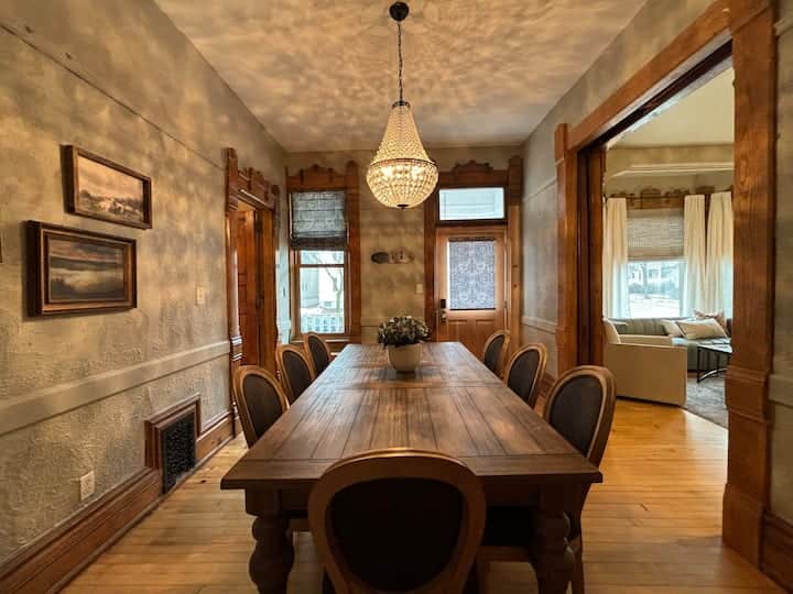 Warm and inviting dining room with a grand wooden table, vintage details, and a sparkling chandelier