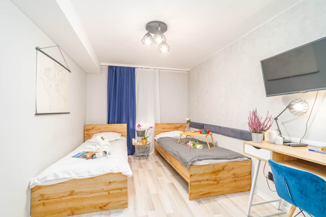 Przestronny pokój z dwoma pojedynczymi łóżkami, wygodnym biurkiem i telewizorem.