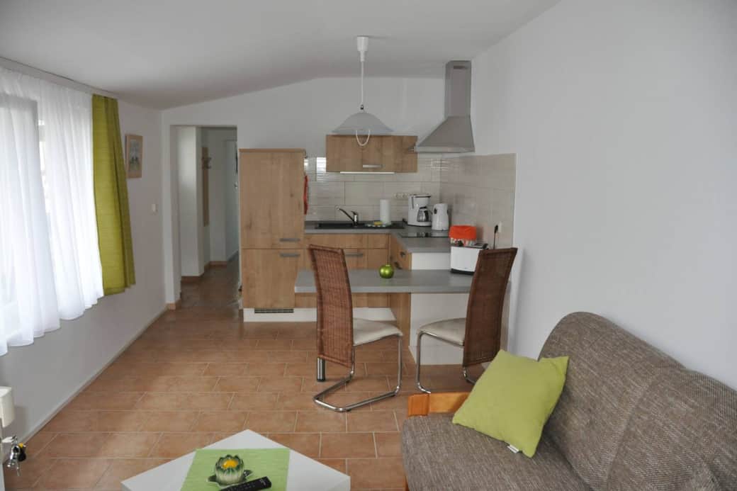 Küchenzeile mit Herd (ohne Backofen) , Kühlschrank ohne Gefrierfach, Kaffeemaschine, Toaster, Wasserkocher, Kochgeschirr, Essgeschirr, Gläser und Besteck sowie Kindergeschirr und -besteck.