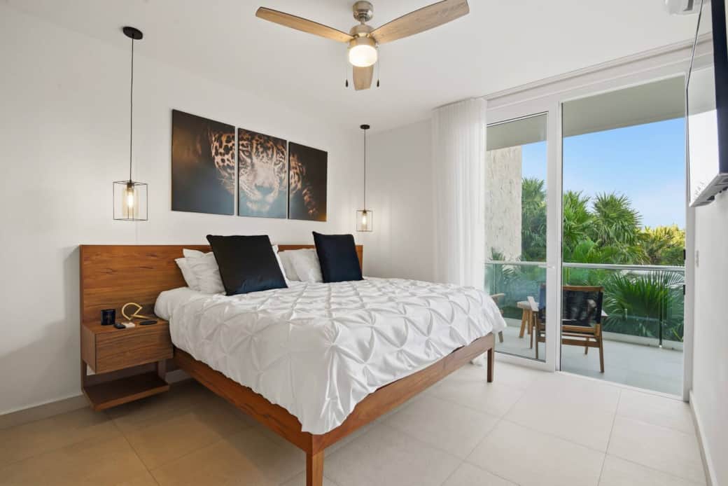 Relax in this inviting bedroom featuring a plush king bed, TV, AC, ceiling fan, ample wardrobe, and room-darkening shades for a restful sleep. Sliding glass doors lead to a private balcony with beautiful greenery and pool views. Relax in this inviting bedroom featuring a plush king bed, TV, AC, ceiling fan, ample wardrobe, and room-darkening shades for a restful sleep. Sliding glass doors lead to a private balcony with beautiful greenery and pool views.