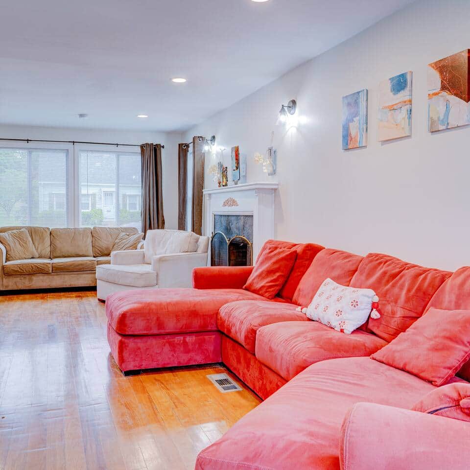 Living Room Bliss: Vibrant seating invites relaxation, while large windows offer plenty of light and views of charming neighborhood.