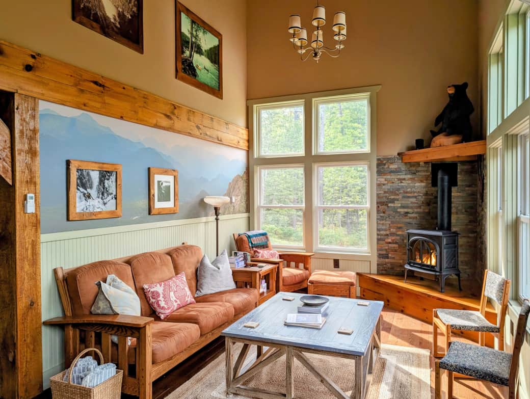 A cozy living room with comfortable seating, a cozy fireplace with stone surround, with large window