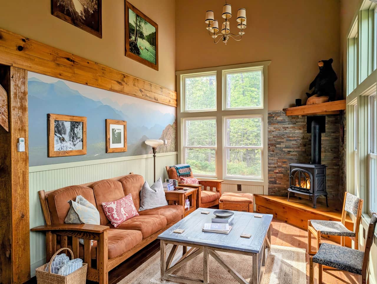 A cozy living room with comfortable seating, a cozy fireplace with stone surround, with large window