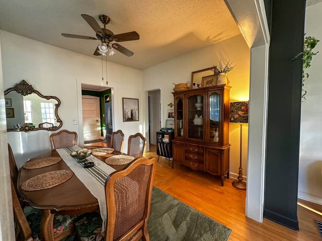 Inviting dining room with a vintage wooden table for six, warm lighting, and a classic china cabinet—perfect for shared meals, morning coffee, or evening conversation.