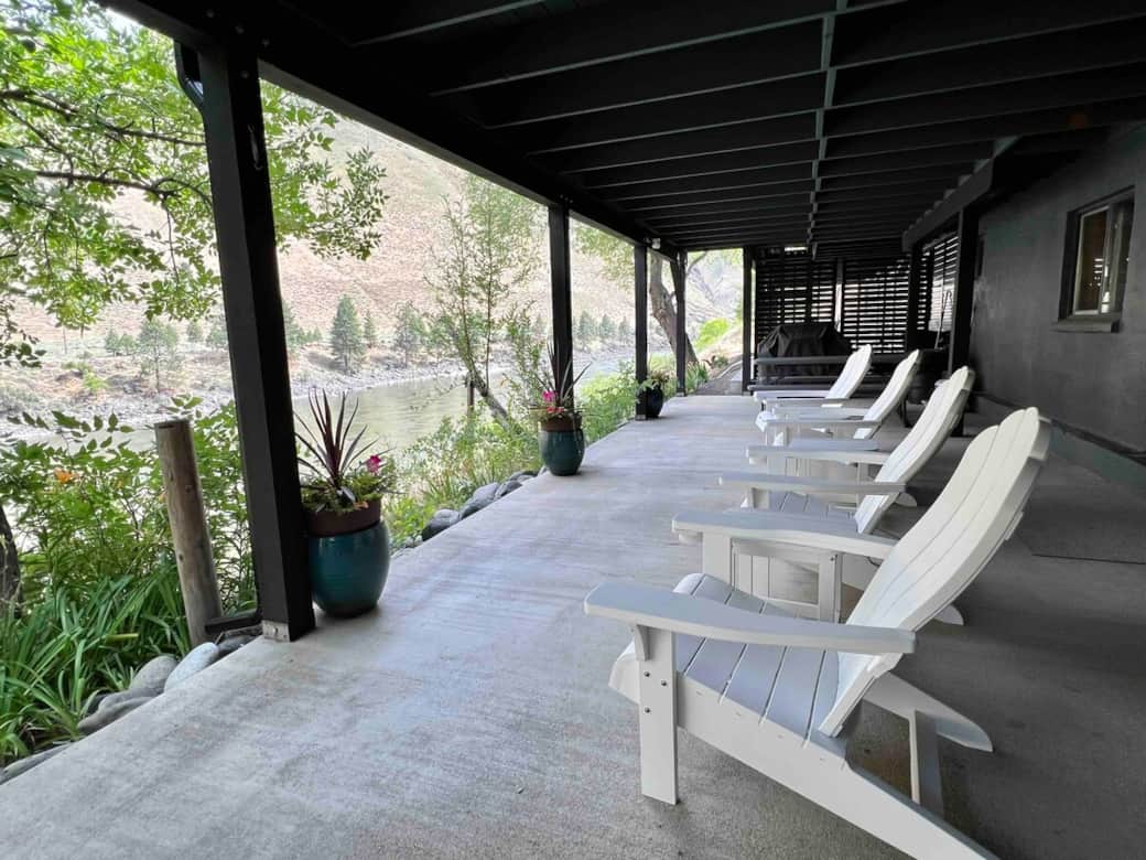 Large covered patio with BBQ, picnic table, propane fire pit and seating with a river view