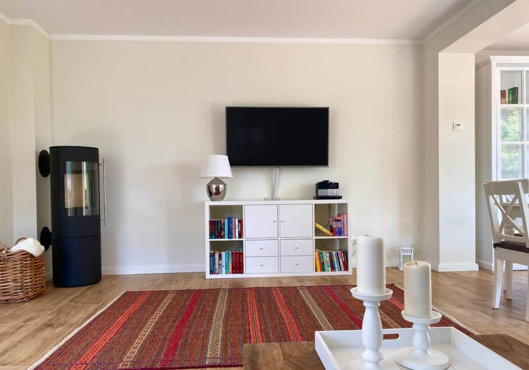 Wohnzimmer mit Blick auf Kaminofen, Smart TV, Regal mit Büchern, Spielen