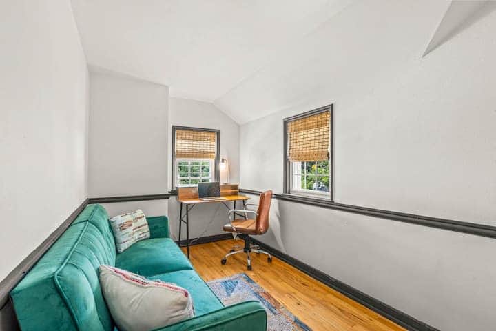 Bright and versatile room featuring a comfortable green sofa bed and dedicated workspace.