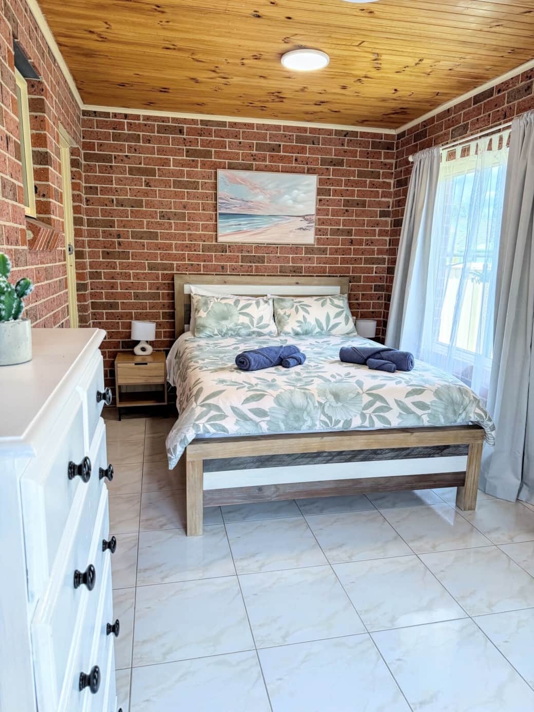 Comfortable Queen-size bed with fresh linen, four pillows, two shower towels, two face towels, a large wardrobe, bedside lamps, and an air-conditioning system.