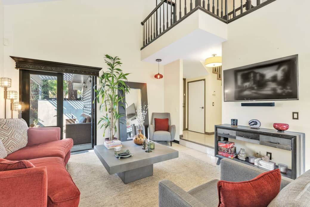 Living room area with mounted TV, sleek furniture, and doors to the patio.