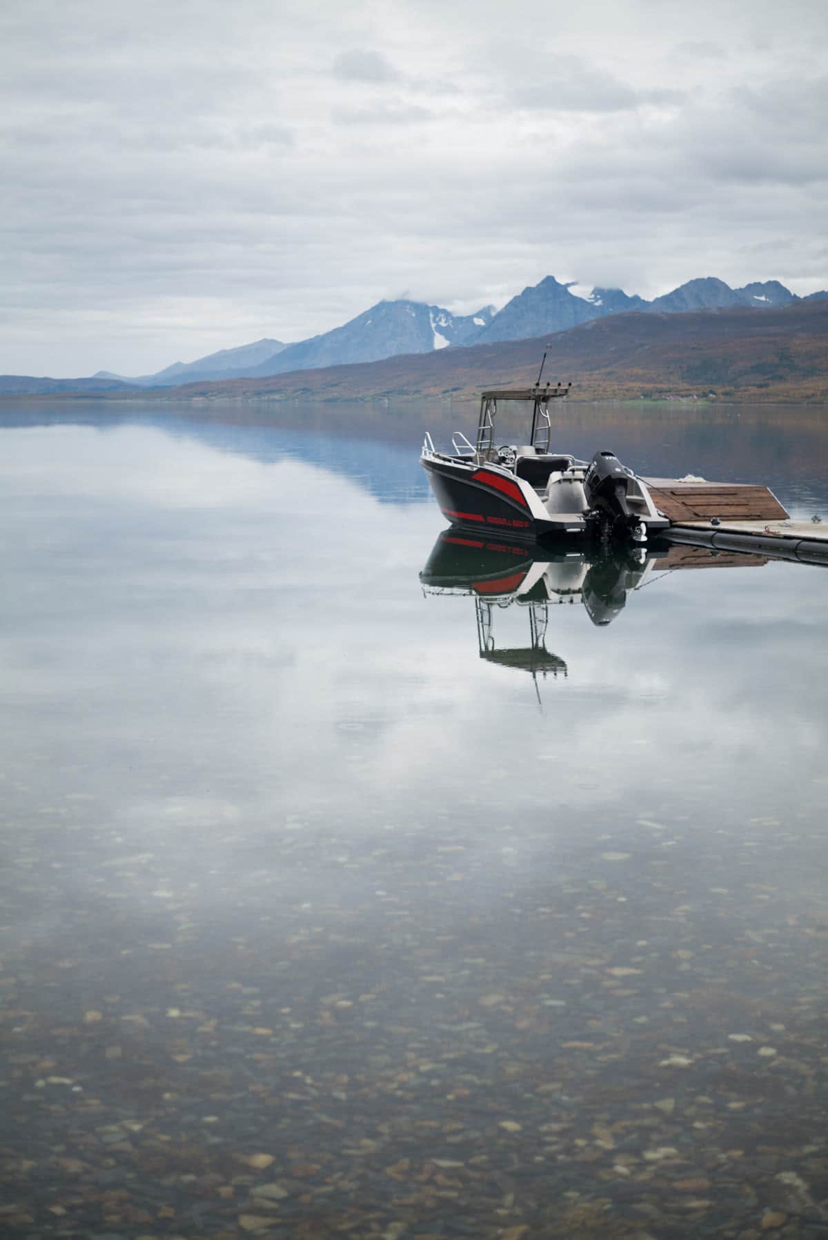 Boot am Steg, gespiegelt im stillen Fjord