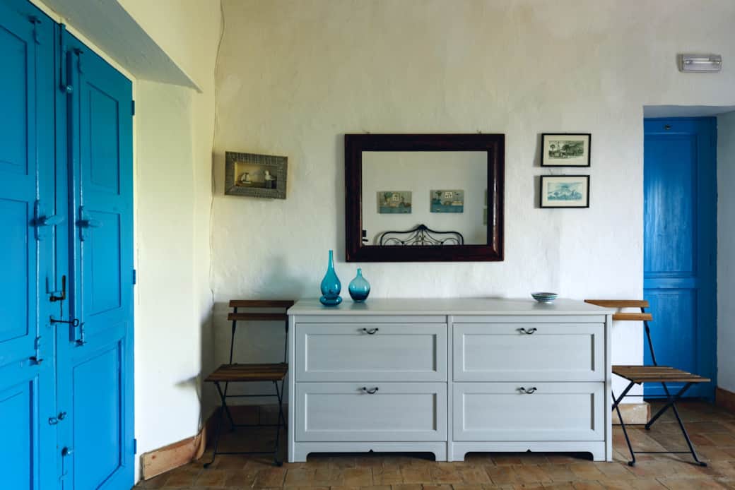 Camera luminosa in stile eoliano con arredi essenziali e porte blu tradizionali Camera luminosa in stile eoliano con arredi essenziali e porte blu tradizionali