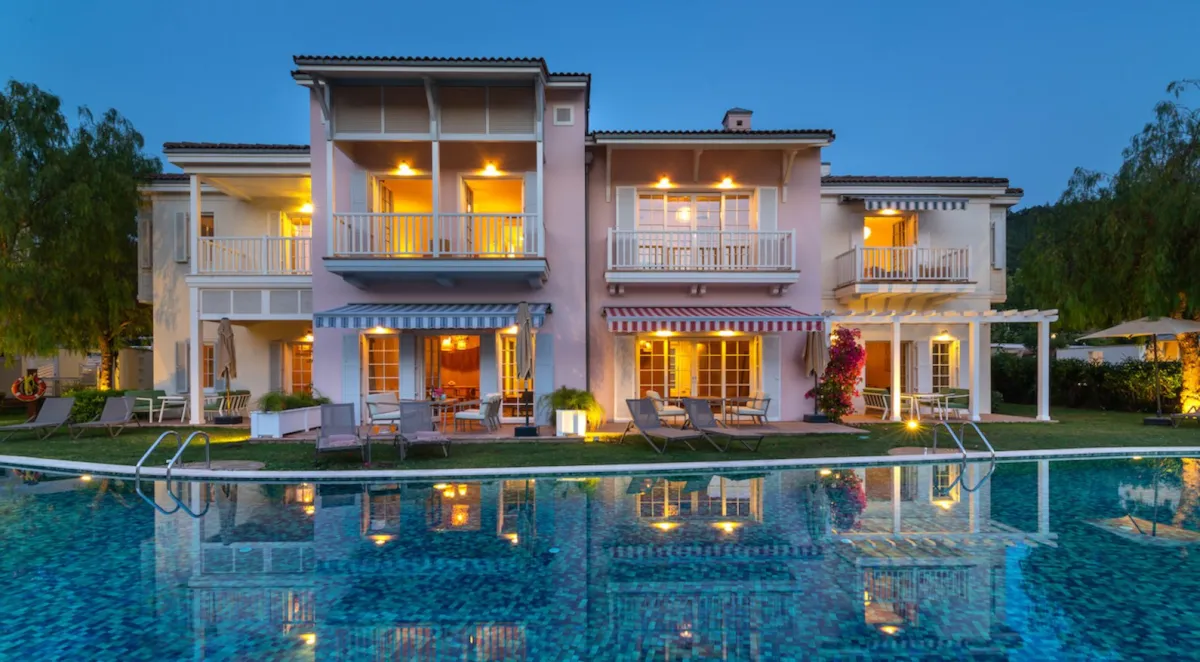 Exterior view of Portville B1 043 with a pool, garden, and illuminated balconies in Göcek.