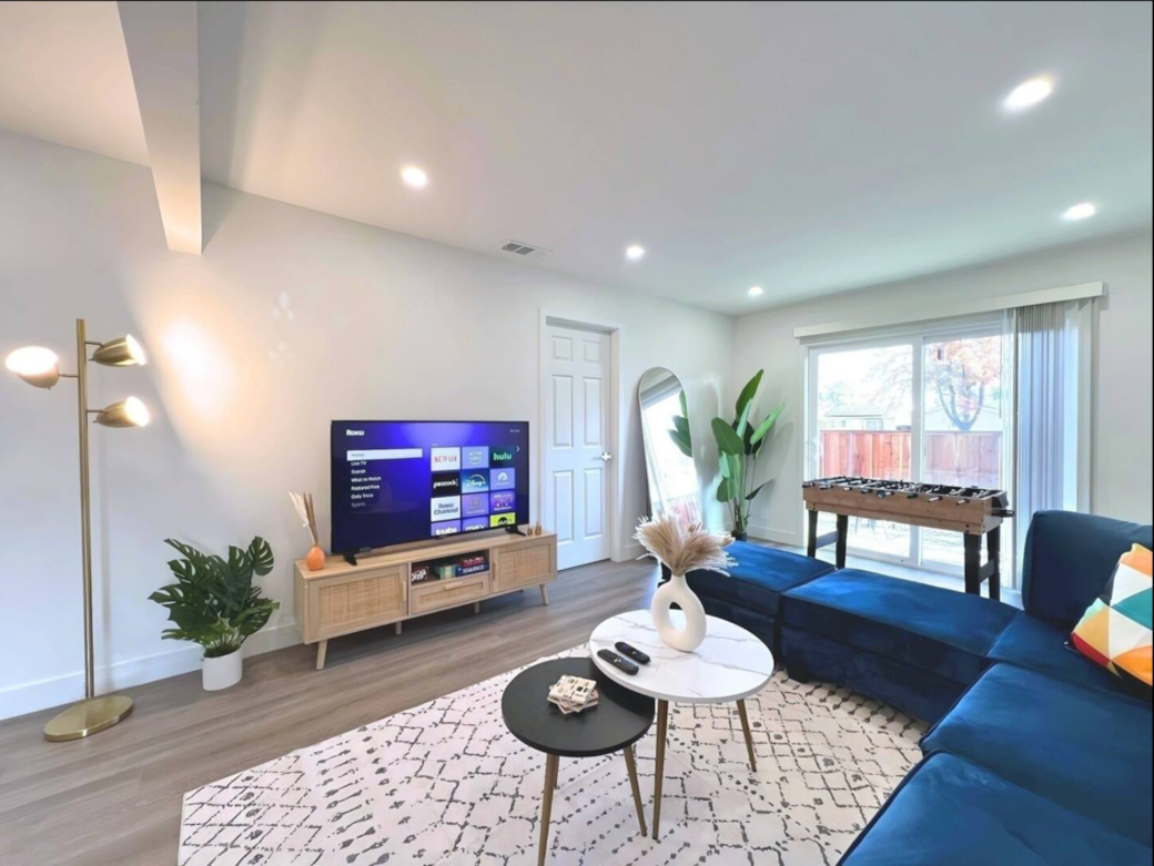 Sleek living room with comfortable seating, large TV, and a foosball table for entertainment. 
