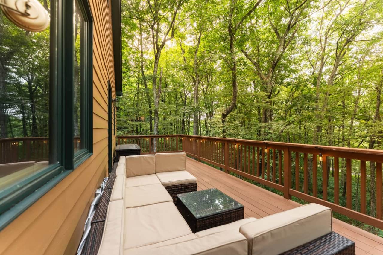 Covered deck lounge overlooking the trees — a peaceful morning coffee spot.