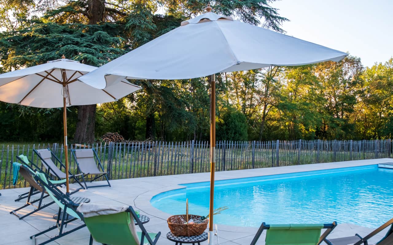 Espace piscine aménagé avec 2 parasols, 8 transats et 2 tables basses.