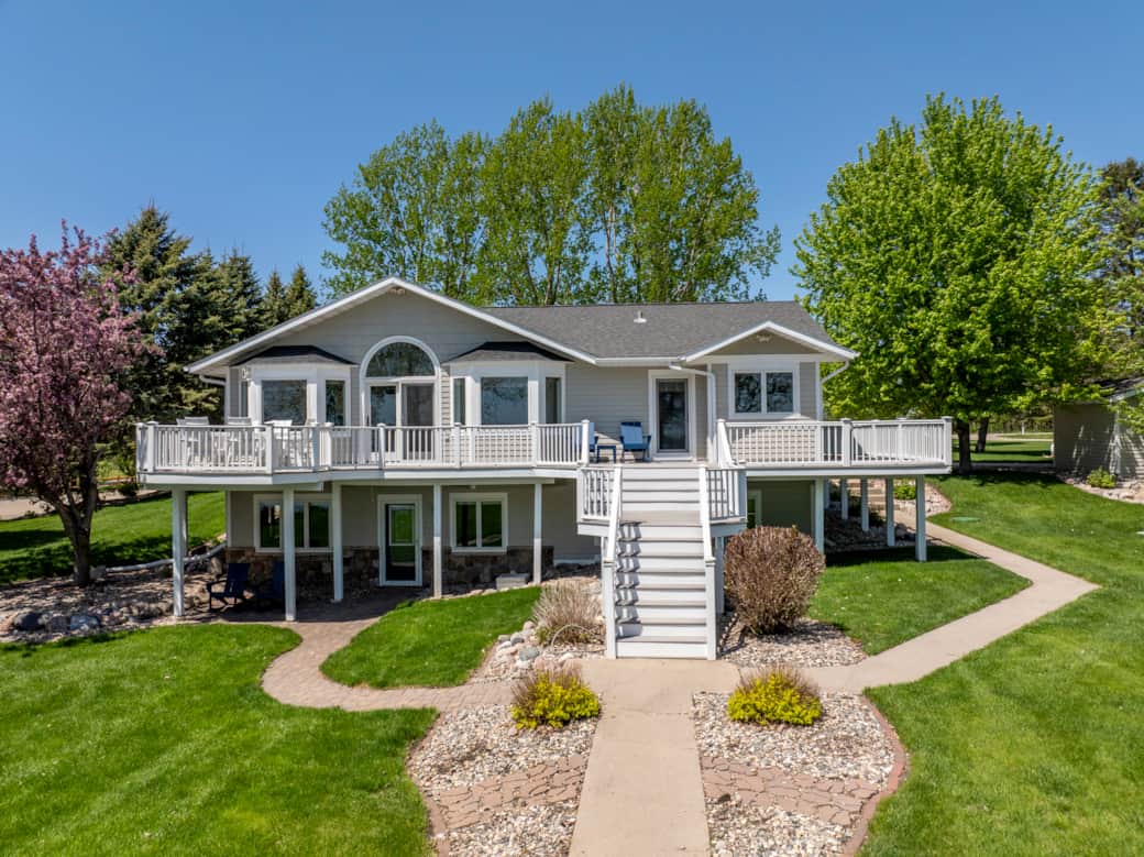Lakeside house view with large yard and wrap around deck Lakeside house view with large yard and wrap around deck