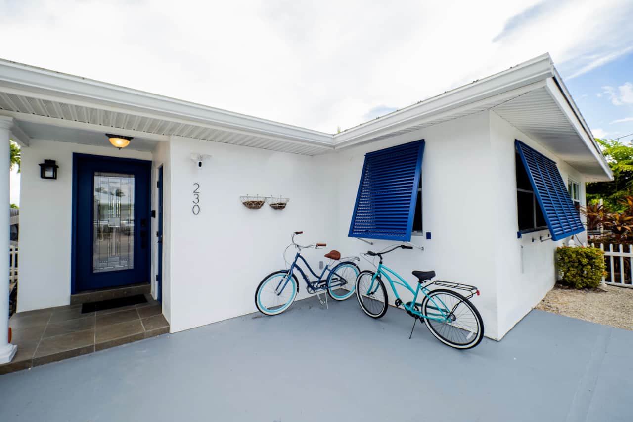 The front of the house: covered parking, bright navy shutters, and two bikes ready to roll.
