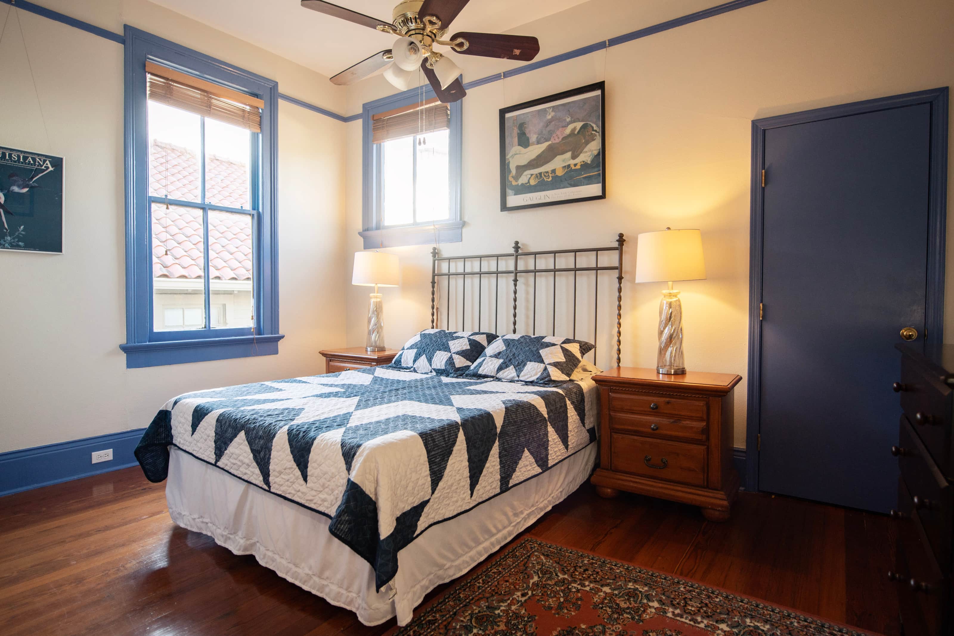 A wide-angle view of a guest room with a bed, nightstands, lamps, and a window